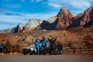 Three riders posing with Polaris Slingshots in Southern Utah surrounded by Zion's red rock mountains.