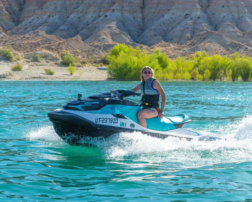 Woman riding a premium Sea-Doo jet ski across a scenic lake in St. George, Utah, enjoying a smooth and exciting watersports adventure